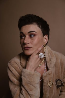 Une femme élégante porte une bague en perles blanches et un manteau de fourure beige