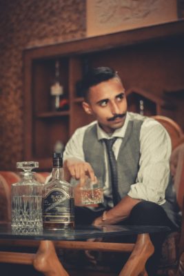 Un homme élégant savoure un whisky installé sur un fauteuil club en cuir luxueux 