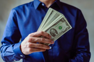 un homme en chemise tient une liasse de billets