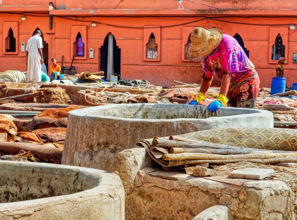 Un artisan est penché au-dessus d'un bassin de pierre contenant des préparations pour le tannage du cuir 