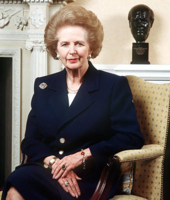 Margaret Thatcher assise sur un siège en tissu devant une cheminée 