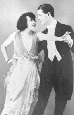 photo en noir et blanc du couple en tenue de soirée, en pieds, de Mistinguett et Maurice Chevalier 