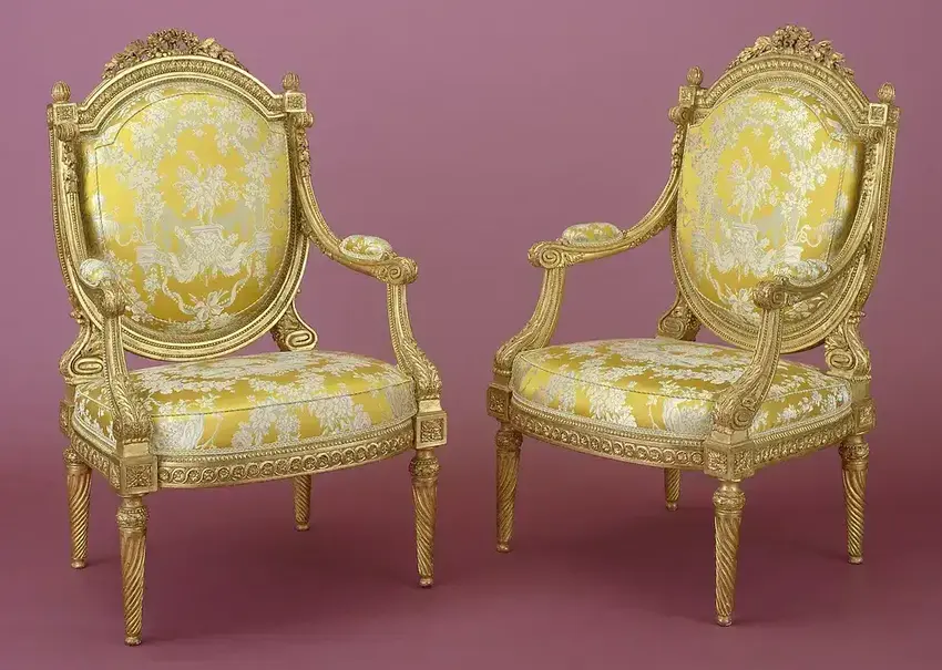 Deux sièges Louis VX avec sa structure recouverte de feuilles d'or et le dossier et assise rembourrées et recouverts d'un tissu ornemental