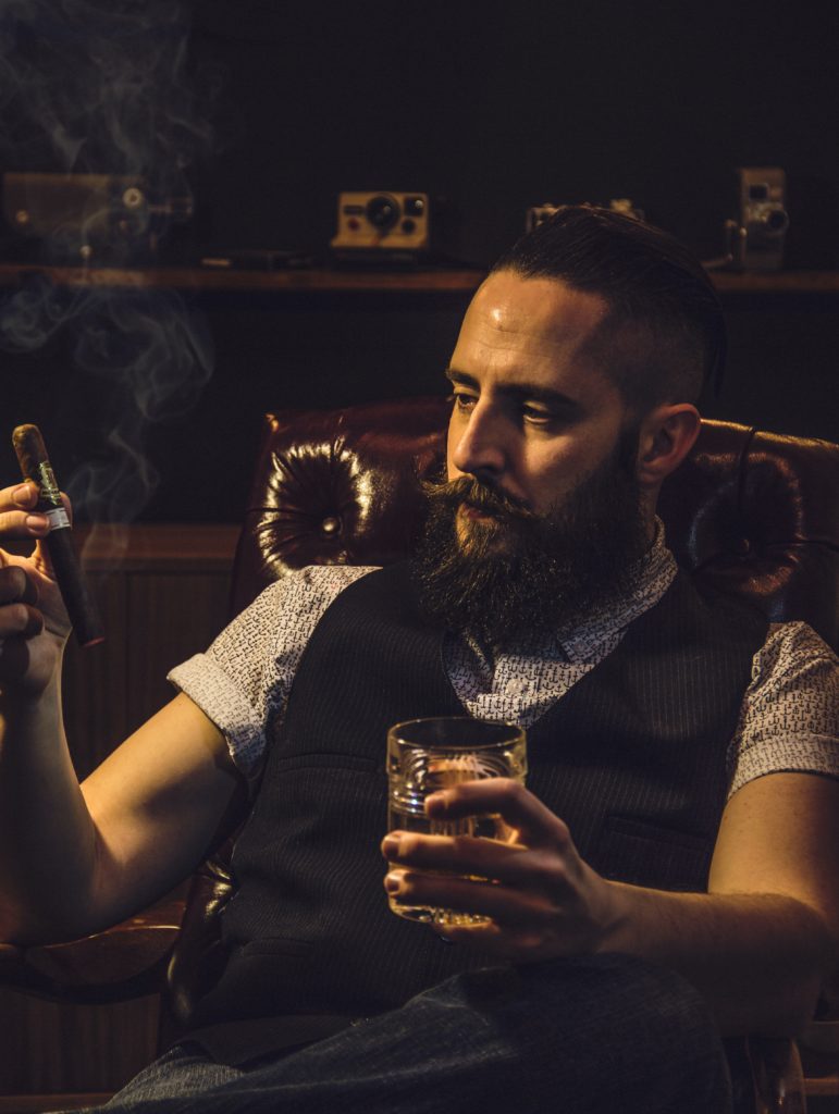 Gentleman savourant un cigare et un whisky dans son fauteuil club 