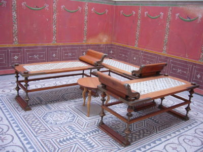 Salon de la Rome Antique avec des sièges-lits en bois et assises en cuir tressé.