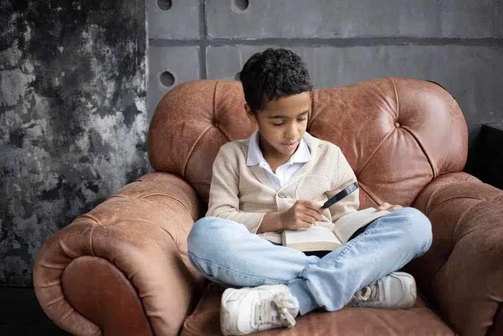 Un enfant qui lit sur un fauteuil en cuir vintage