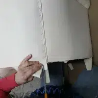 Artisan qui découpe une pièce de cuir sur un fauteuil club en cours de fabrication 