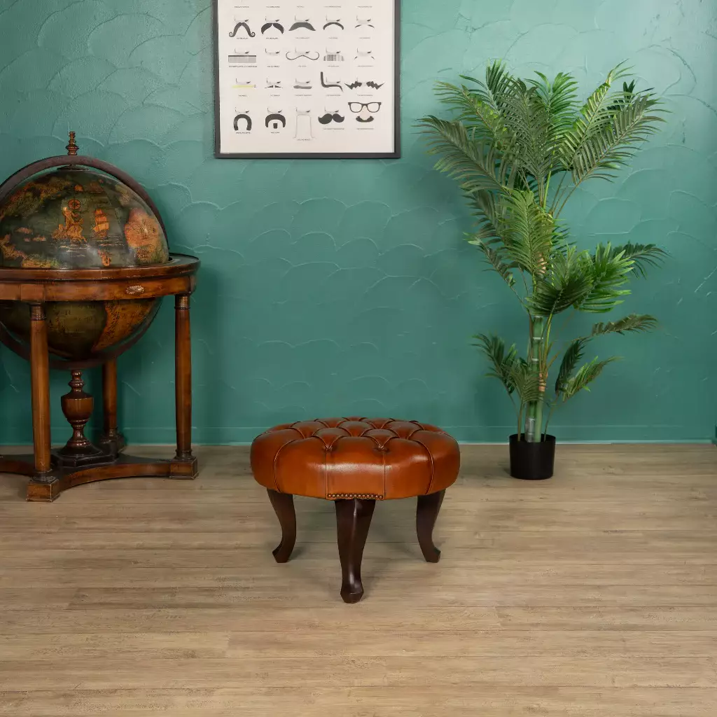 Repose-pieds Chesterfield rond en cuir Havane pleine fleur dans un salon élégant