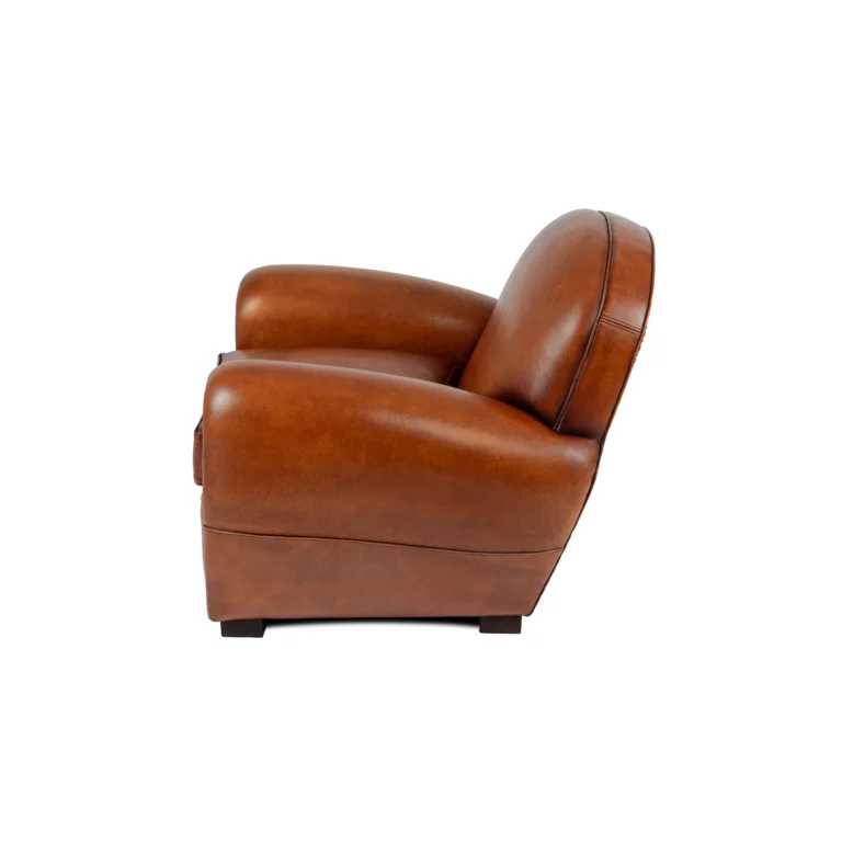 Fauteuil club Raymond en cuir de basane couleur havane, dossier rond et accoudoirs galbés, vue de côté sur fond blanc